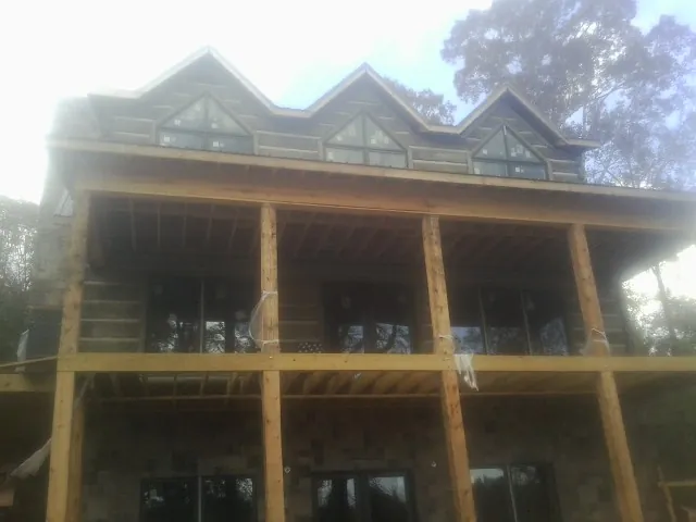 Dormers and porch framing on a large log home under construction — Roof Coating work by our crew in Stockton